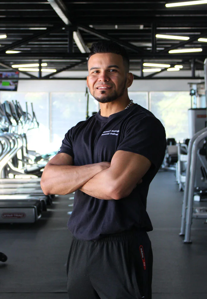Gamaliel Bastidas, entrenador personal, brazos cruzados en gimnasio.